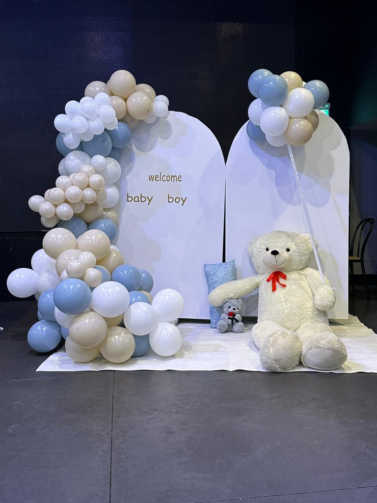 בלונים בתכלת, בז׳ ולבן ליד לוחות welcome baby boy ודובי לבן