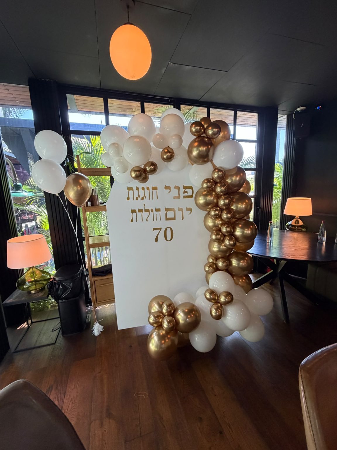 מיצב בלונים לבן וזהב עם שלט יום הולדת 70 במסעדה